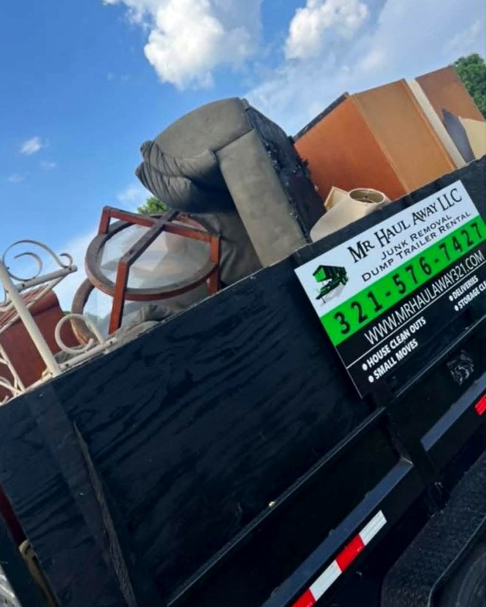 Dump trailer stacked with furniture, loaded by the crew